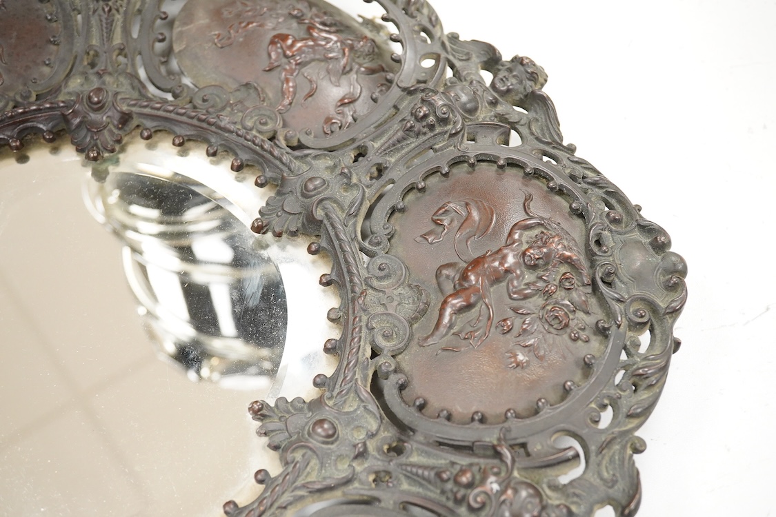 An ornate circular decorative bronzed metal putti decorated wall mirror, 40cm